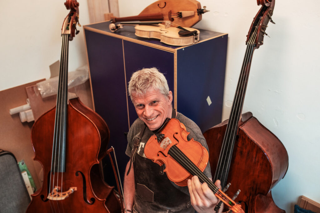 Harrie repareert een viool in zijn tijdelijke werkruimte via bruikleenovereenkomst